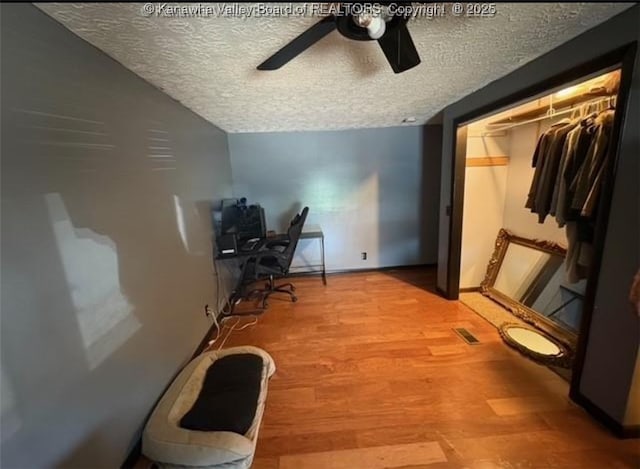 office area featuring baseboards, wood finished floors, ceiling fan, and a textured ceiling