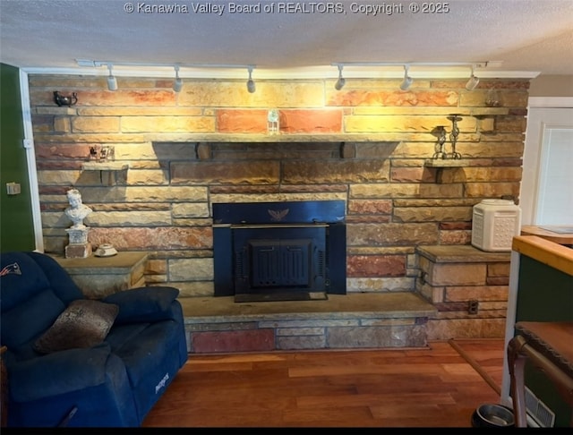 living room featuring wood finished floors, rail lighting, a textured ceiling, and a fireplace