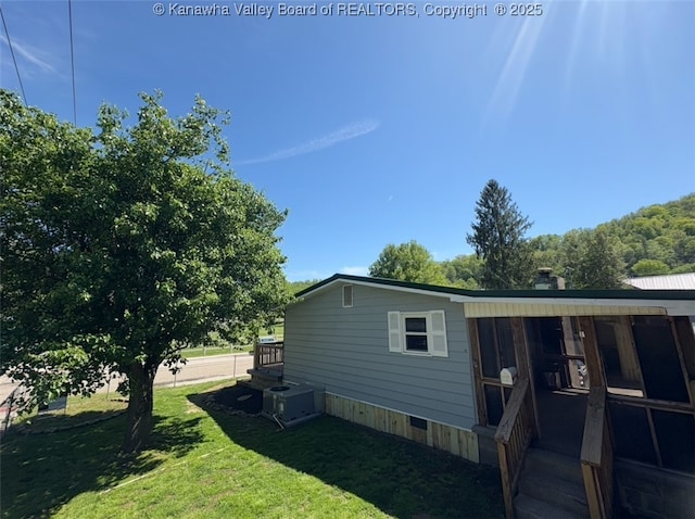 view of home's exterior with a lawn and central AC