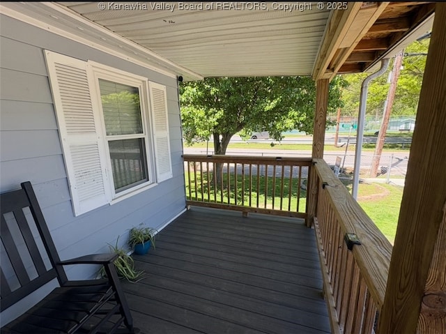 wooden deck with a lawn and covered porch