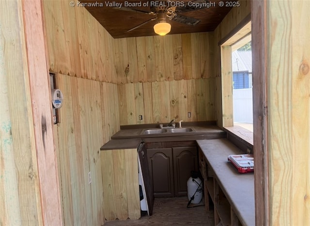 bar featuring wooden walls, a sink, ceiling fan, and wood finished floors