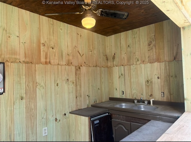 bar featuring wood walls, ceiling fan, and a sink