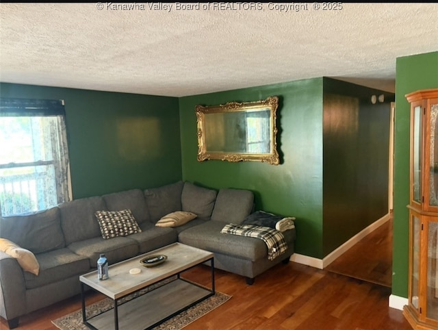 living room with a textured ceiling, wood finished floors, and baseboards