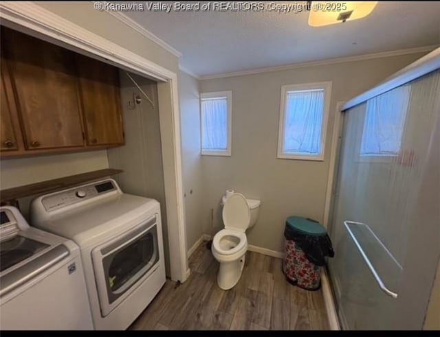 clothes washing area featuring wood finished floors, laundry area, washing machine and clothes dryer, baseboards, and crown molding