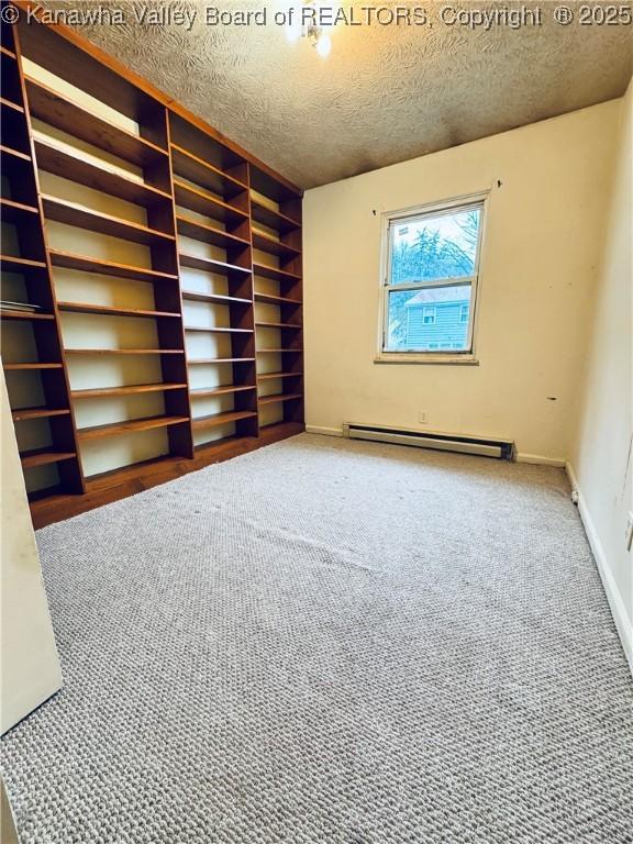 carpeted spare room featuring baseboards, a baseboard radiator, and a textured ceiling
