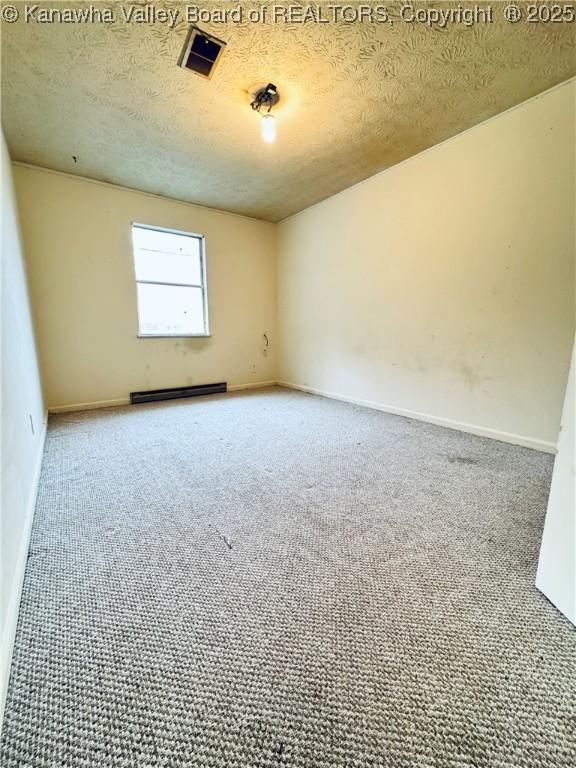 spare room featuring visible vents, baseboards, a textured ceiling, baseboard heating, and carpet flooring