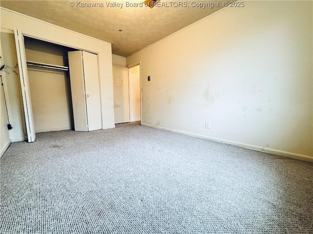 unfurnished bedroom with a closet, baseboards, carpet flooring, and a textured ceiling