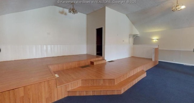 additional living space featuring a notable chandelier, vaulted ceiling, and carpet floors