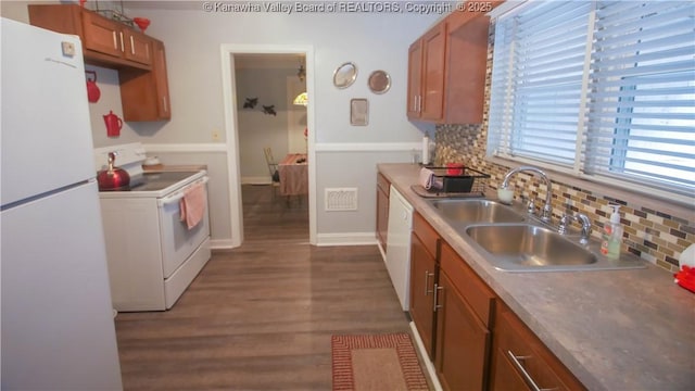 kitchen featuring a sink, white appliances, dark wood-style floors, brown cabinets, and decorative backsplash