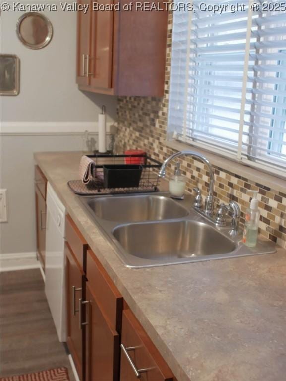 kitchen featuring a sink, tasteful backsplash, white dishwasher, and brown cabinets
