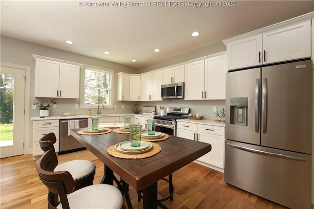 kitchen featuring light wood-style floors, a sink, white cabinets, and stainless steel appliances