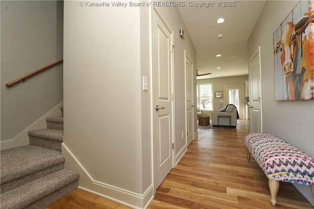 hall featuring light wood-style flooring, baseboards, stairway, and recessed lighting