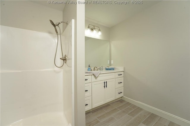 bathroom with a shower, vanity, baseboards, and wood finish floors