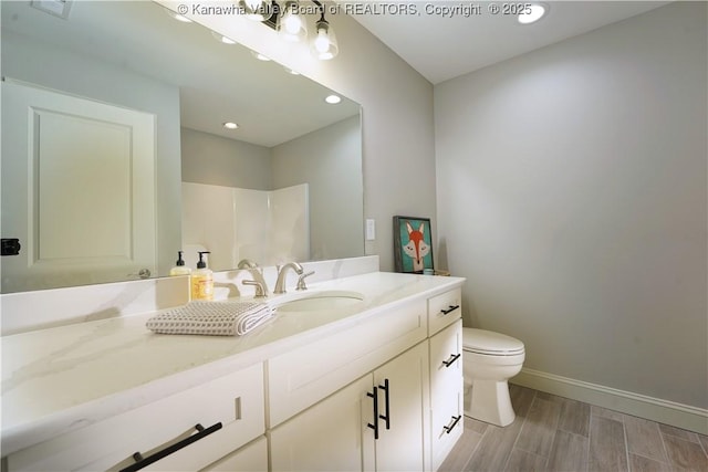 full bathroom featuring vanity, baseboards, wood finish floors, recessed lighting, and toilet