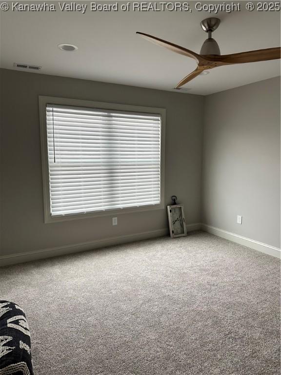 carpeted empty room featuring visible vents, baseboards, and a ceiling fan