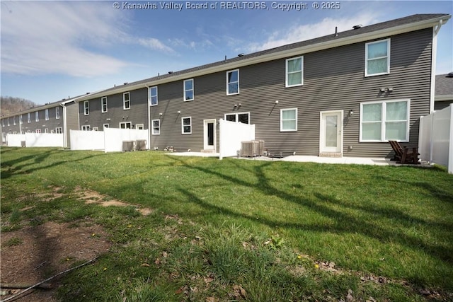 rear view of house featuring a yard, cooling unit, and fence