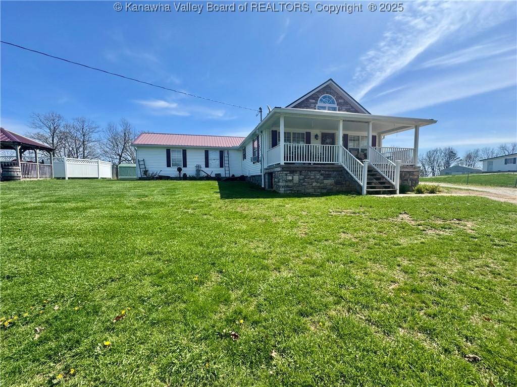 view of front of property featuring a front yard, a porch, and metal roof