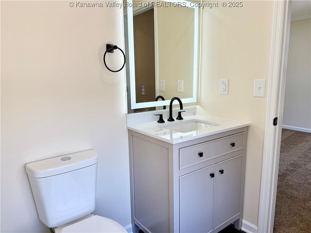 half bathroom featuring toilet, vanity, and baseboards