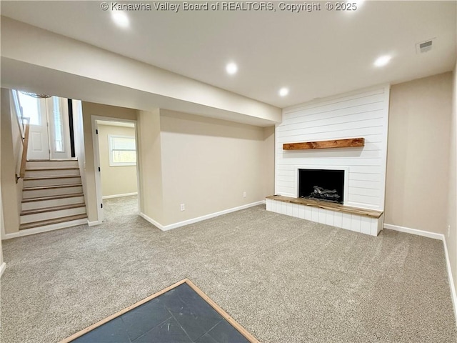 unfurnished living room with a tiled fireplace, carpet floors, baseboards, and visible vents