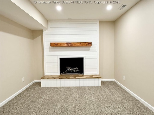 unfurnished living room featuring a large fireplace, visible vents, baseboards, and carpet flooring