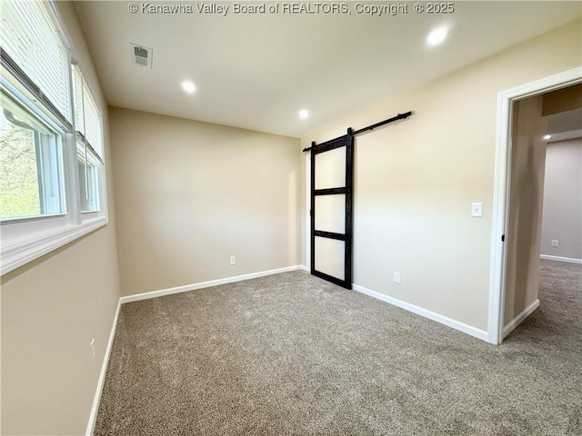 carpeted spare room featuring recessed lighting, a barn door, visible vents, and baseboards