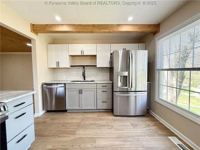kitchen with a sink, backsplash, beam ceiling, and stainless steel appliances