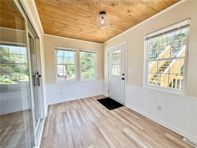 doorway with visible vents, wooden ceiling, a wainscoted wall, and wood finished floors