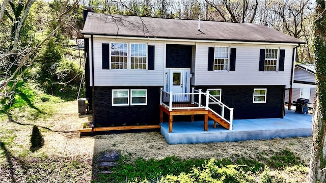 view of front of property featuring brick siding, central AC unit, and a patio