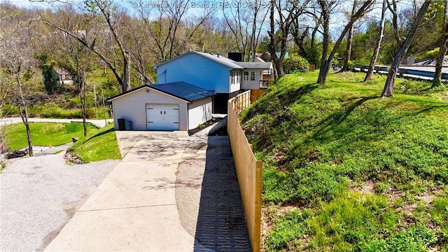 view of property exterior featuring concrete driveway, a garage, and a lawn