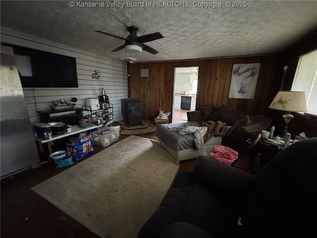 living room featuring a wood stove, a textured ceiling, and ceiling fan