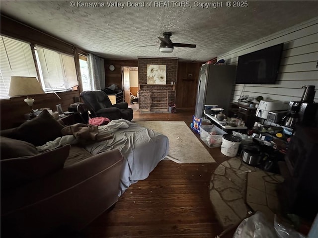 living area featuring wood walls, a ceiling fan, wood finished floors, and a textured ceiling