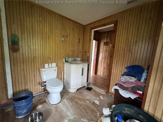 bathroom featuring wooden walls, a sink, toilet, and wood finished floors