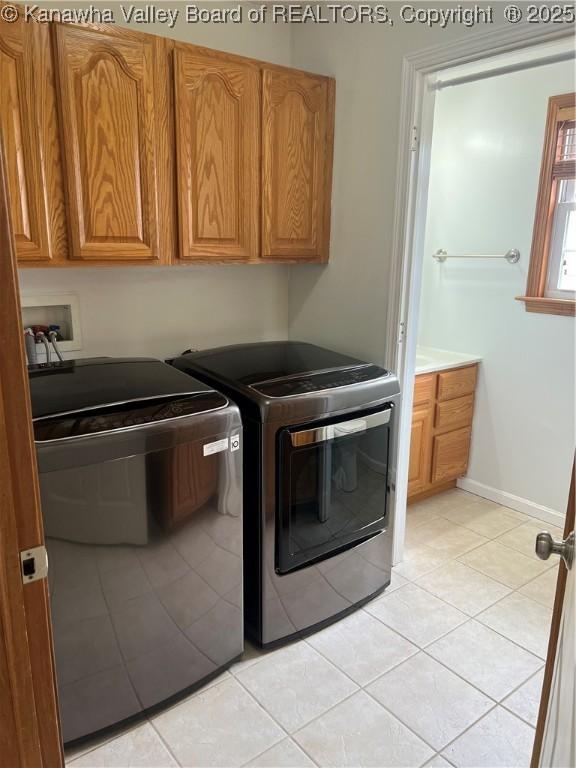 washroom featuring cabinet space, baseboards, washing machine and dryer, and light tile patterned floors