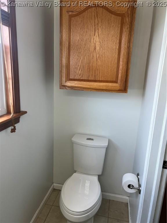 bathroom with toilet, baseboards, and tile patterned flooring