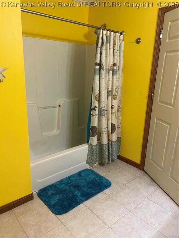 bathroom with shower / bath combo with shower curtain, baseboards, and tile patterned floors
