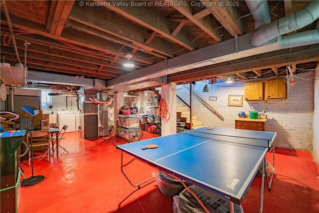 12 Arlington Ct, Charleston, WV 25301 - playroom featuring independent washer and dryer, finished concrete floors, brick wall, and heating unit