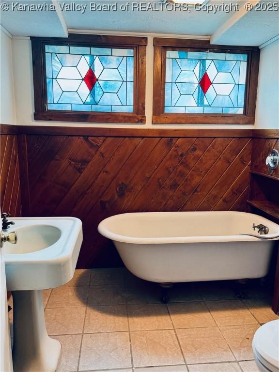 5218 Walnut Valley Dr, Charleston, WV 25313 - full bathroom featuring healthy amount of natural light, a soaking tub, tile patterned flooring, a wainscoted wall, and wood walls