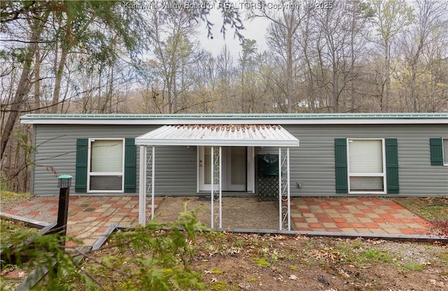 rear view of property with metal roof and a patio