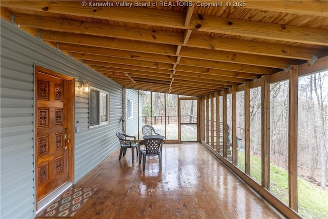 sunroom featuring a healthy amount of sunlight and beam ceiling
