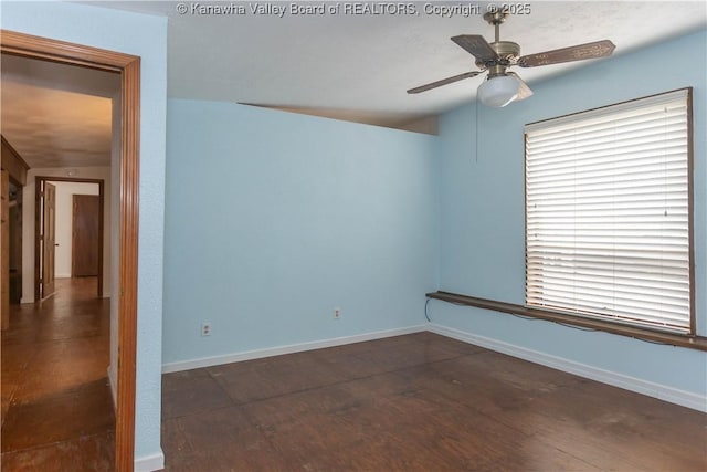 spare room featuring baseboards, a ceiling fan, and dark wood-style floors