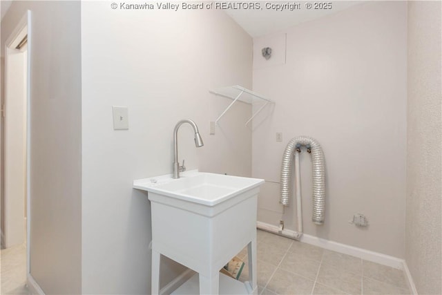 clothes washing area featuring laundry area, light tile patterned flooring, baseboards, and a sink