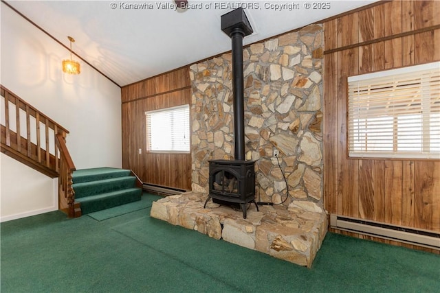 unfurnished living room featuring a baseboard radiator, a wood stove, and carpet flooring