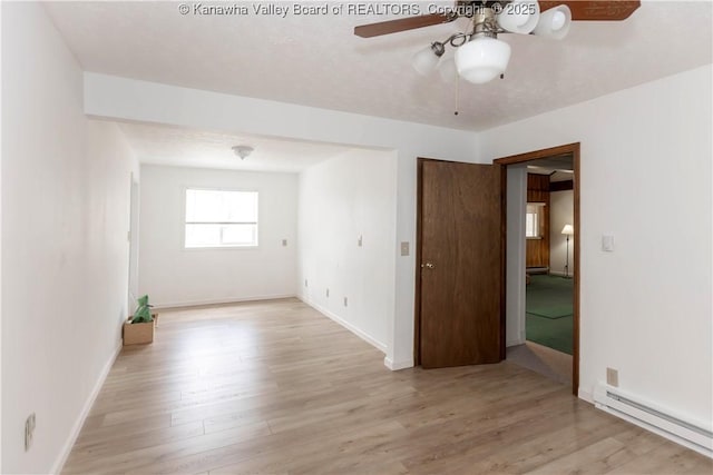 empty room featuring ceiling fan, wood finished floors, a baseboard heating unit, and baseboards