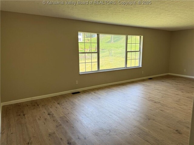 1651 Glenwood Rd, Milton, WV 25541 - spare room featuring a textured ceiling, baseboards, visible vents, and wood finished floors