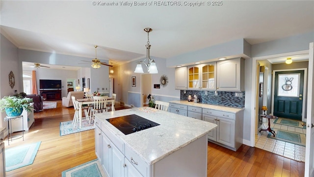83 Lakeview Dr, Nitro, WV 25143 - kitchen featuring light wood-type flooring, a kitchen island, pendant lighting, decorative backsplash, and black electric stovetop