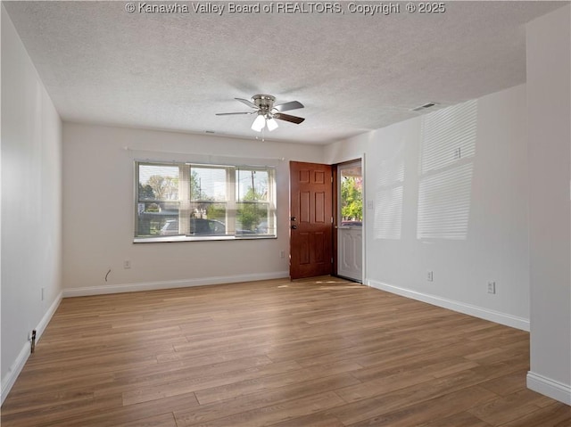 spare room with wood finished floors, visible vents, a ceiling fan, baseboards, and a textured ceiling