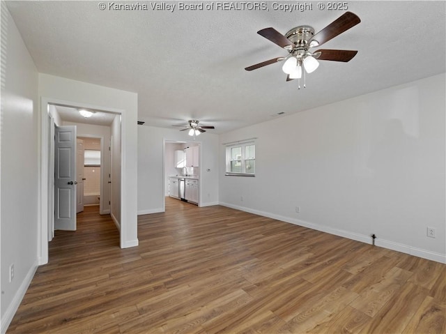 unfurnished bedroom featuring wood finished floors, a textured ceiling, a ceiling fan, and baseboards