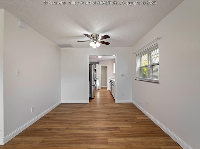 unfurnished room featuring ceiling fan, baseboards, wood finished floors, and a textured ceiling