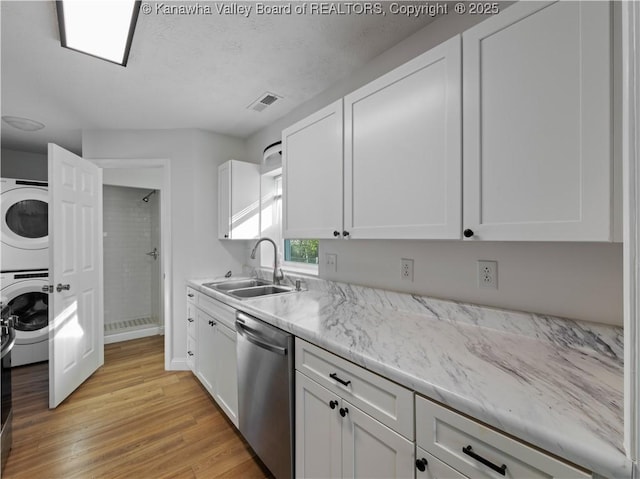 kitchen with stacked washer and dryer, a sink, visible vents, white cabinetry, and dishwasher