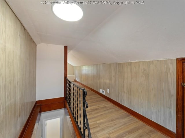 stairway with wood walls, baseboards, vaulted ceiling, and wood finished floors
